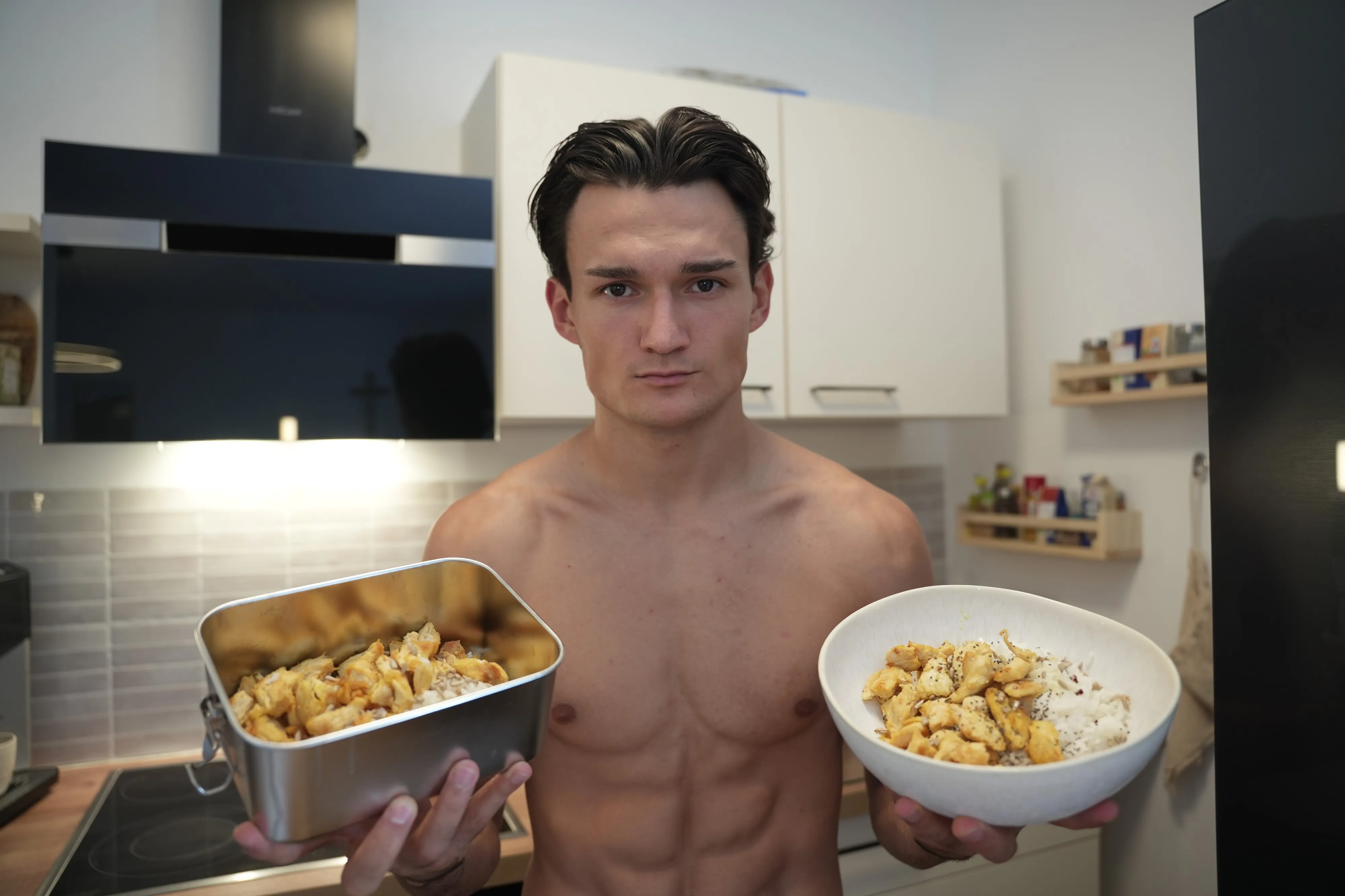 Anto in his kitchen holding two prepared meals
